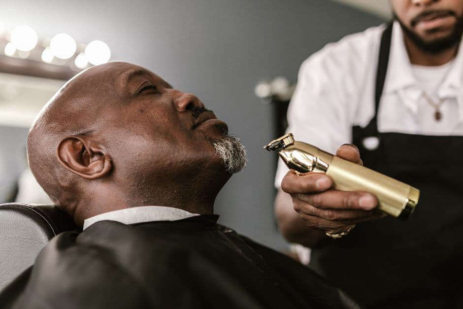 A barber trimming a client’s beard