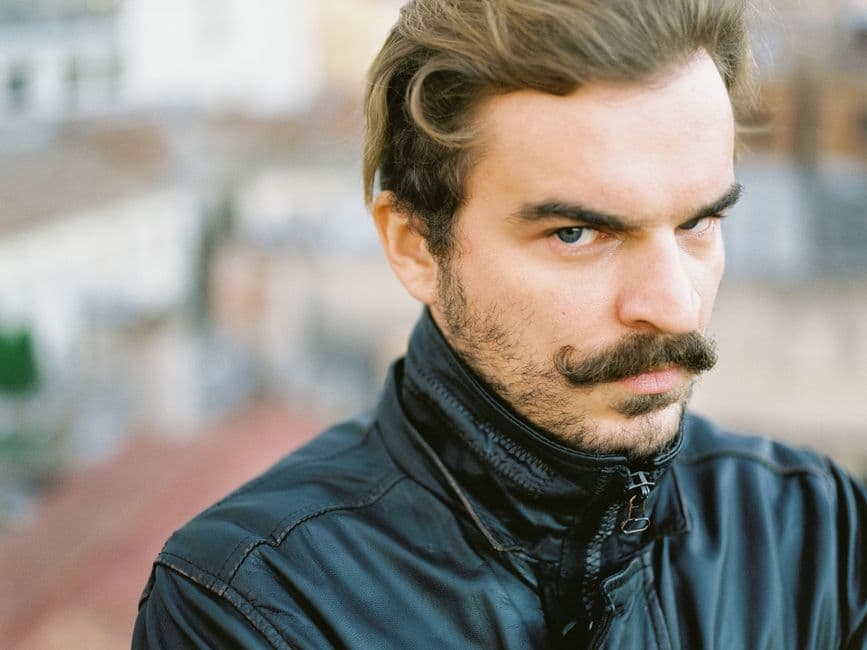 A close portrait of a man with a trimmed mustache