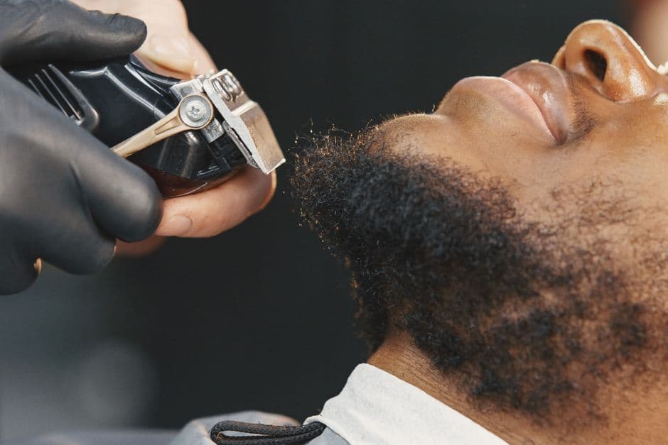 A barber trimming the neckline of a beard