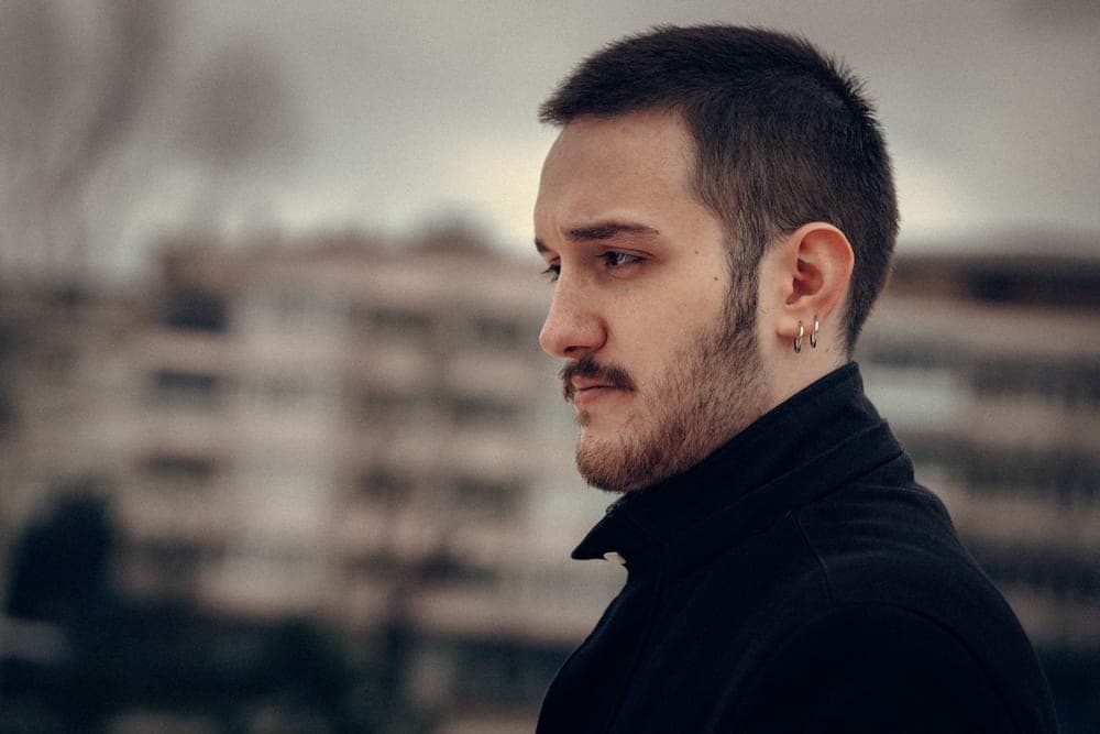 A man with an uneven beard photographed in profile