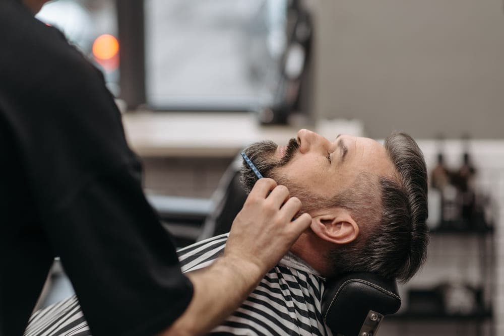 A man combing through his beard with a brush