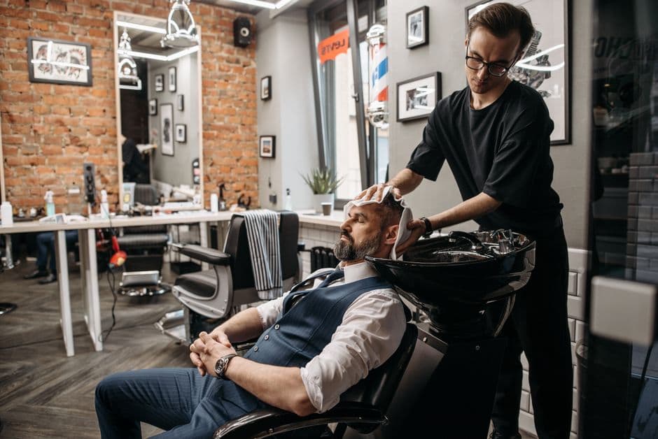 A bearded client having his hair washed in a barbershop