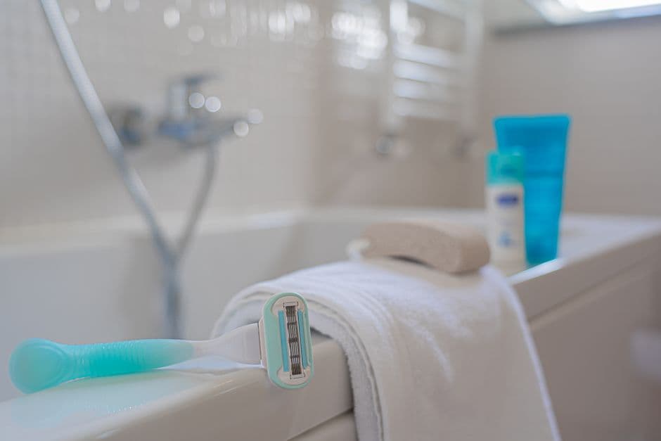 An electric razor beside running water in a bathroom