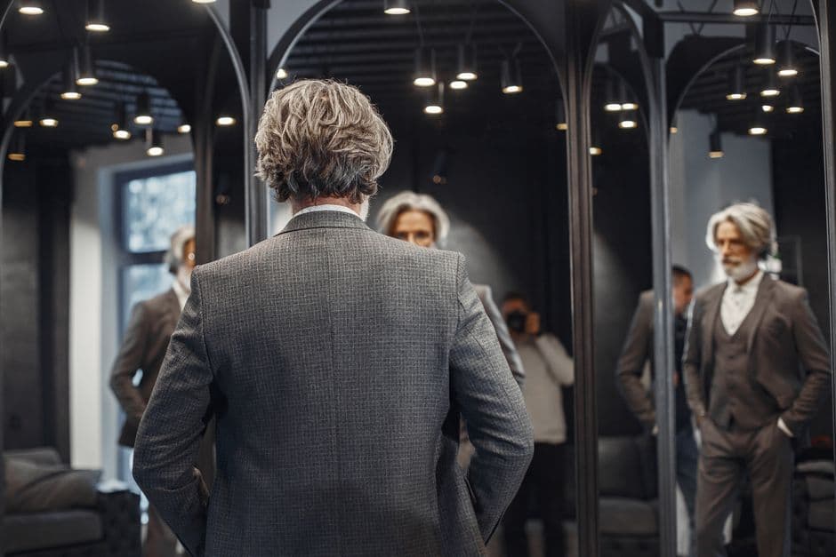 A man with gray hair at a bathroom mirror