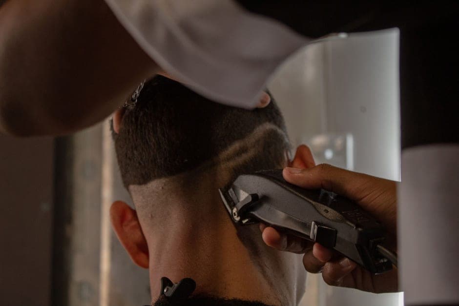 A barber cutting a hard part into short hair with a trimmer