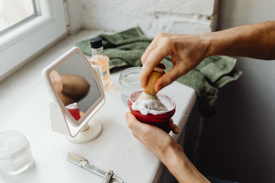 A copper lather bowl and shaving brush on a counter