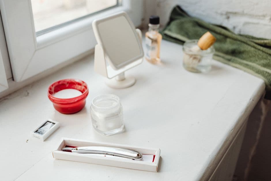 A shaving brush and razor on a shelf