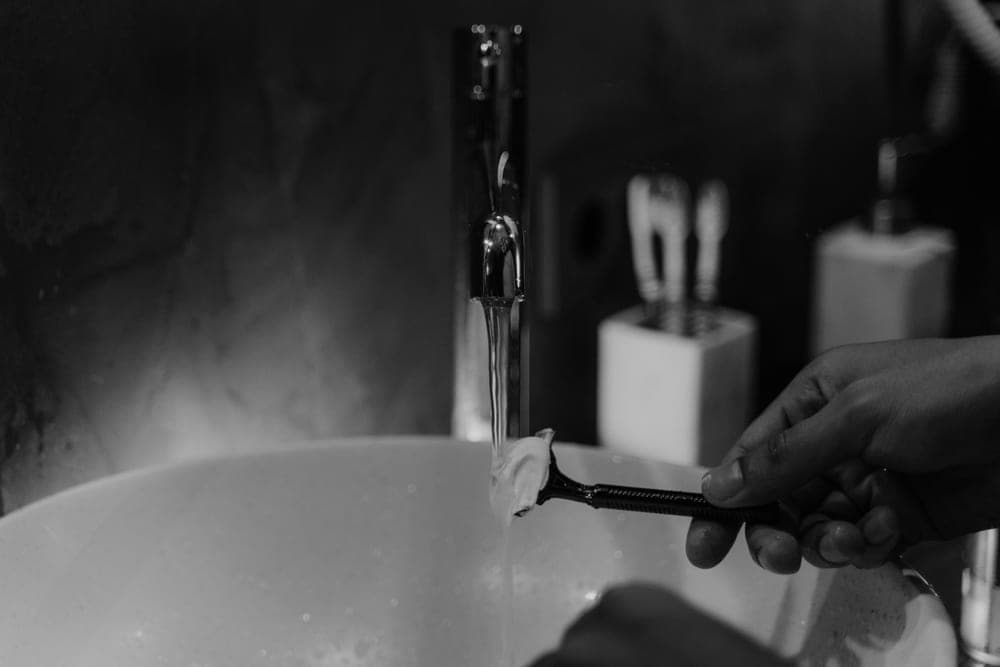 A tube of shaving cream beside a puck of shaving soap