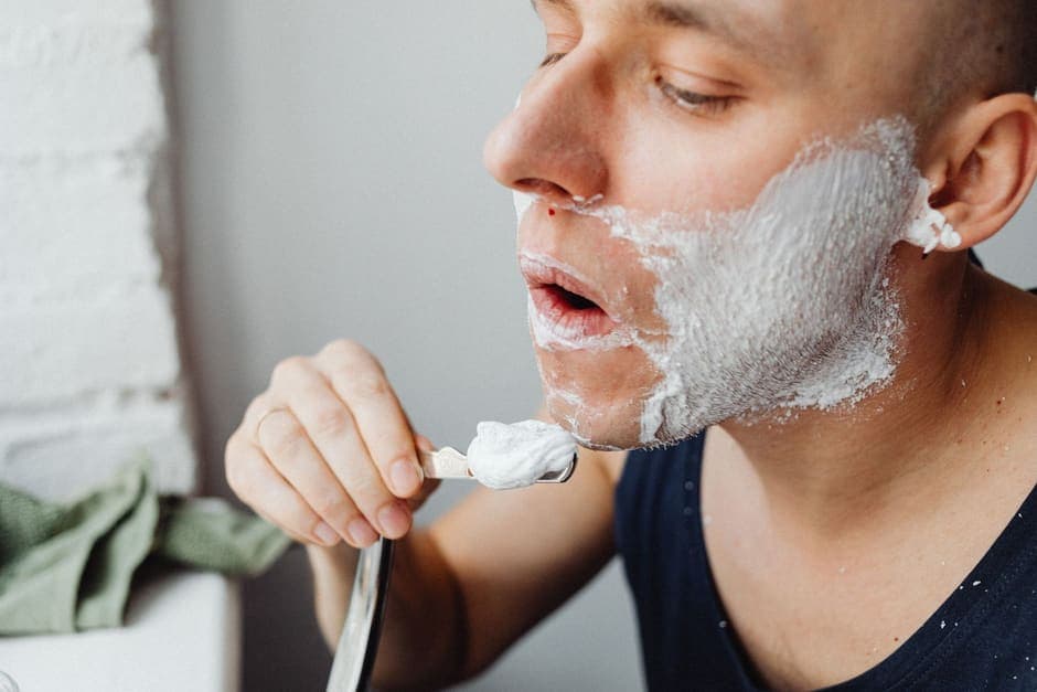 A man applying shaving cream to his face with a brush