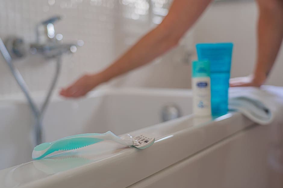 A cartridge razor resting on the edge of a bath