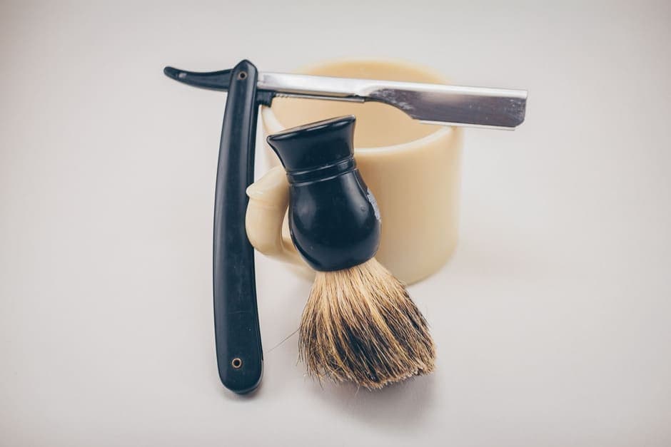 A straight razor, shaving brush and mug arranged as a still life