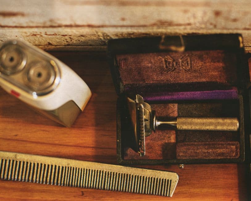 A vintage razor and an electric shaver on a wooden table