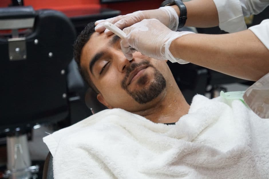 A barber shaving a client with a straight razor