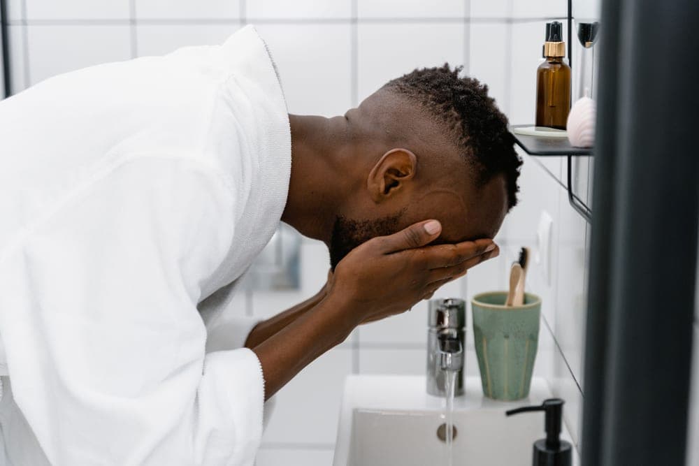 A bottle of face wash beside a sink
