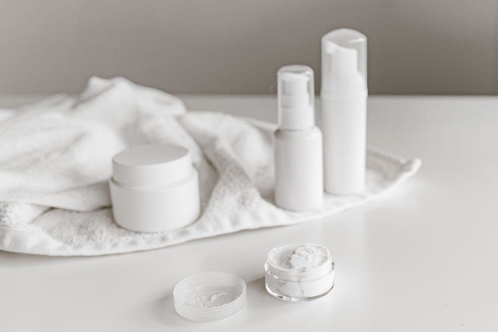 A jar of moisturizer on a plain bathroom surface