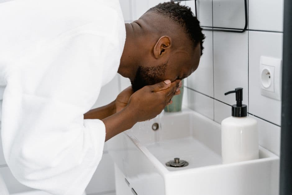 A man washing his face at a bathroom mirror