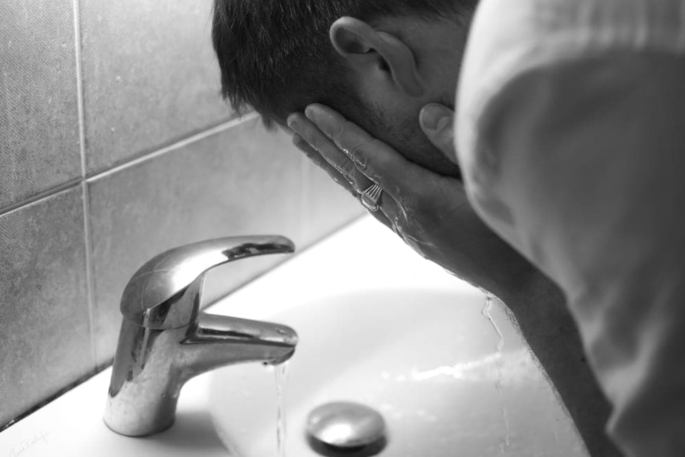 A man rinsing his face at a bathroom sink