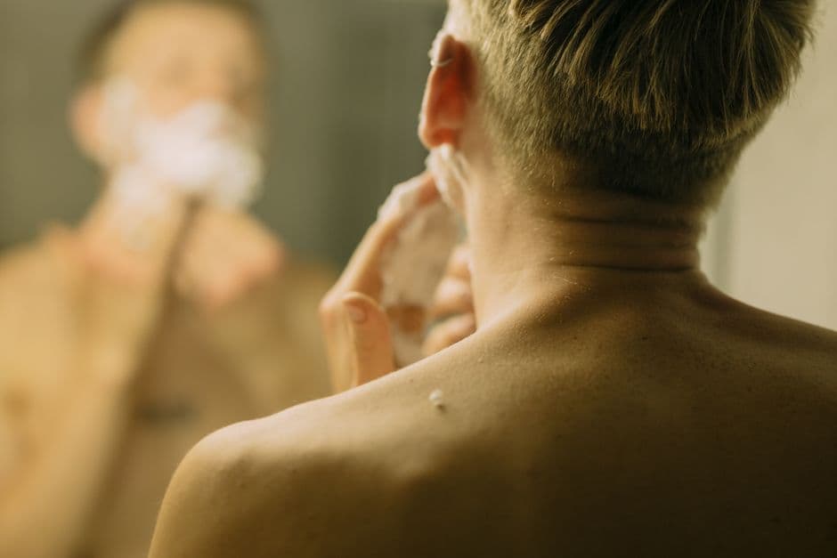 A man examining his face in a bathroom mirror